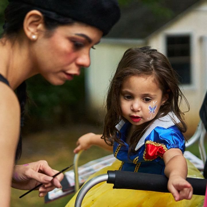 A little girl dressed as Snow White getting a butterfly painted on her cheek