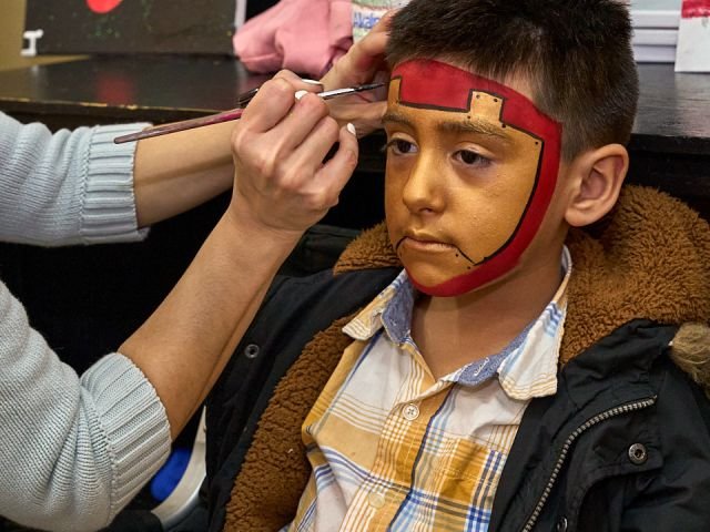 A boy getting an Iron Man mask painted on his face