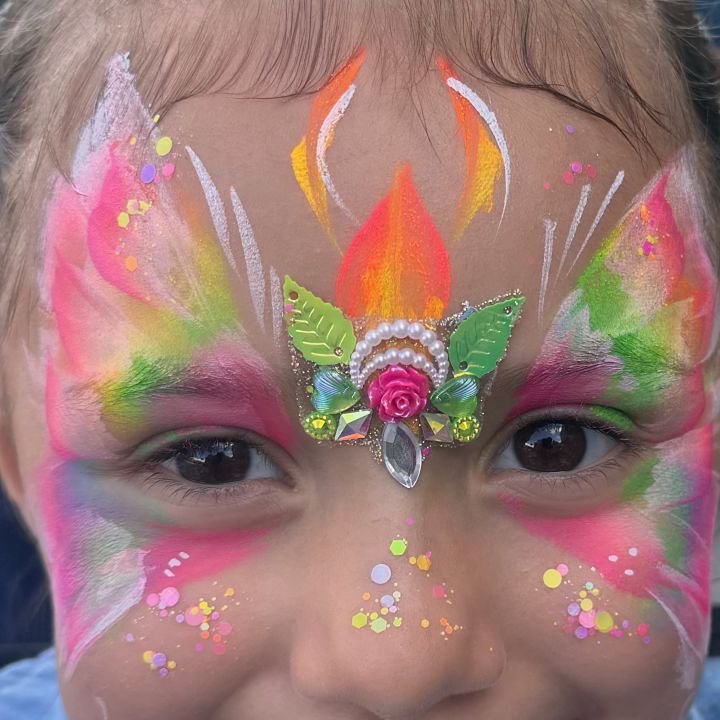 Close-up of a rainbow butterfly face painting with a jeweled rose