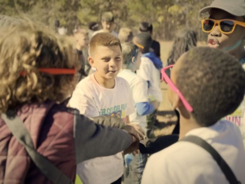 Smiling kids in bright sunglasses at a school color run