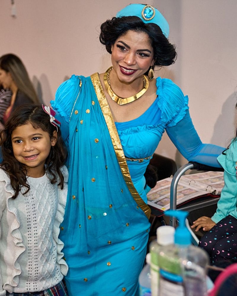 Princess Jasmine posing with smiling, face-painted kids at a birthday party