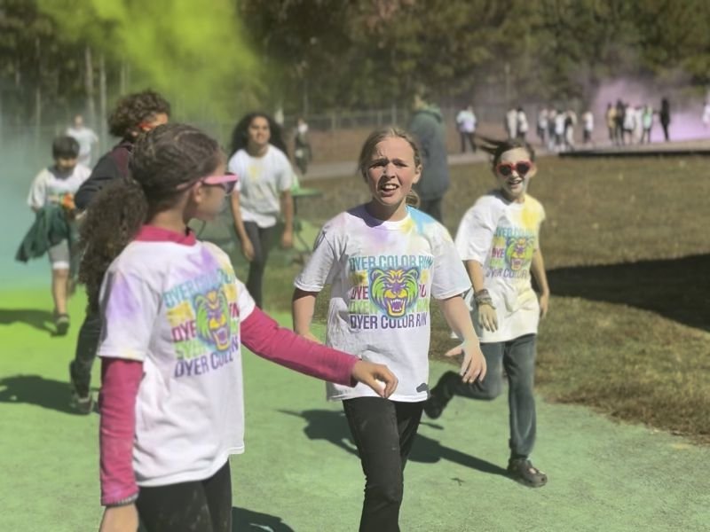Girls smiling as they walk through clouds of colored powder