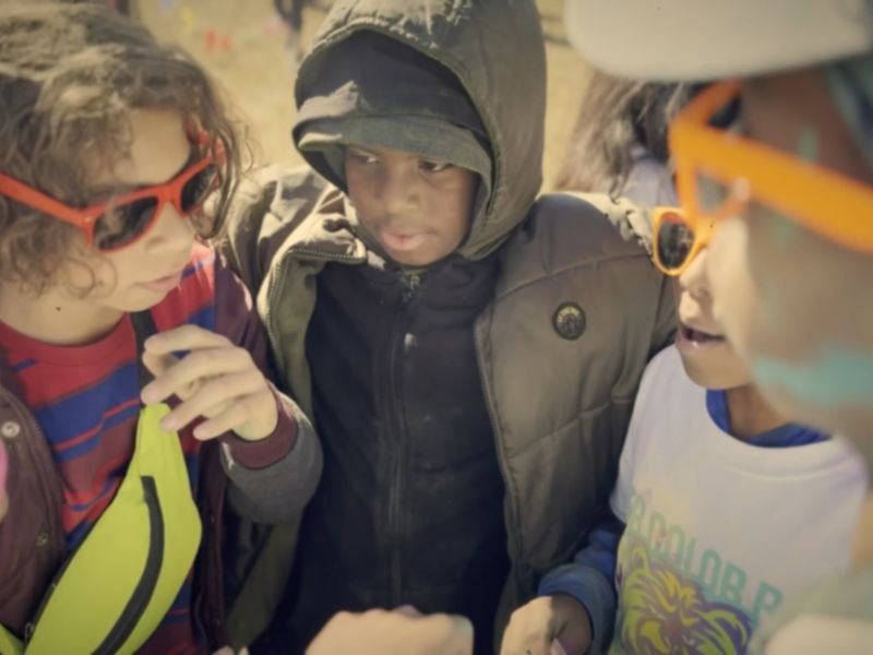Kids in colorful sunglasses huddled together at a school color run