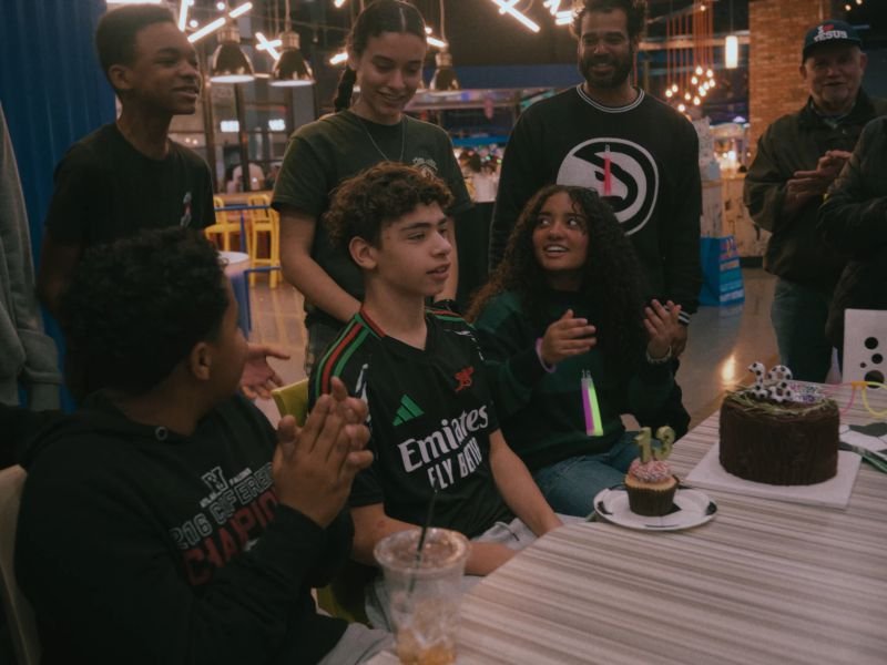 Friends and family gathered around the birthday boy at a bowling alley party