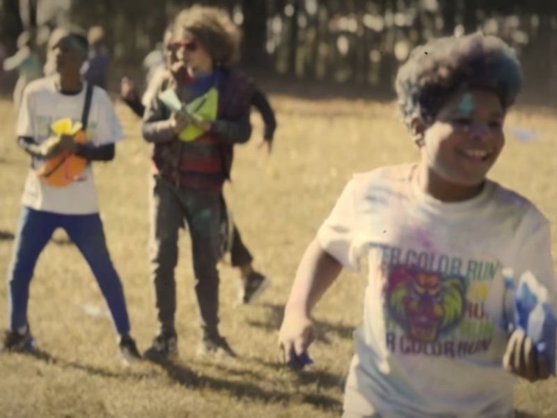 Kids running and laughing across a field during a school color run