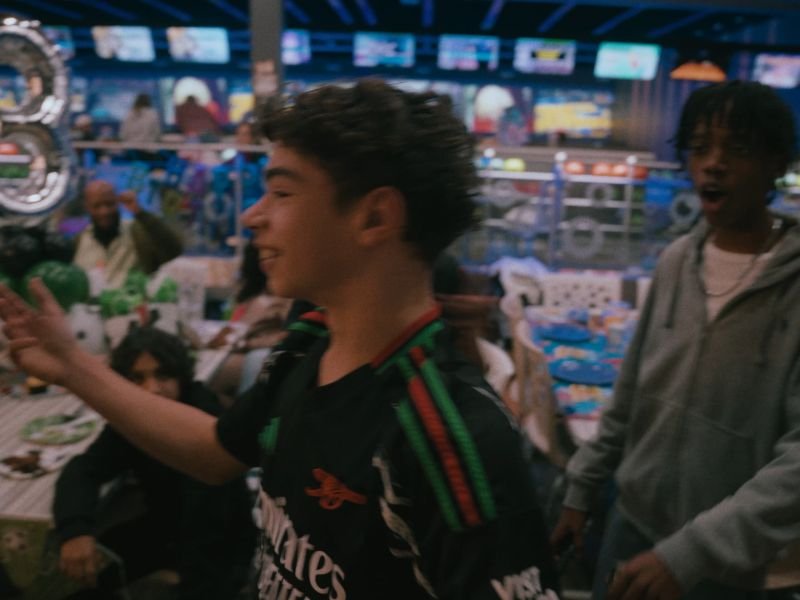 A birthday boy laughing with friends, captured on film at a bowling alley party